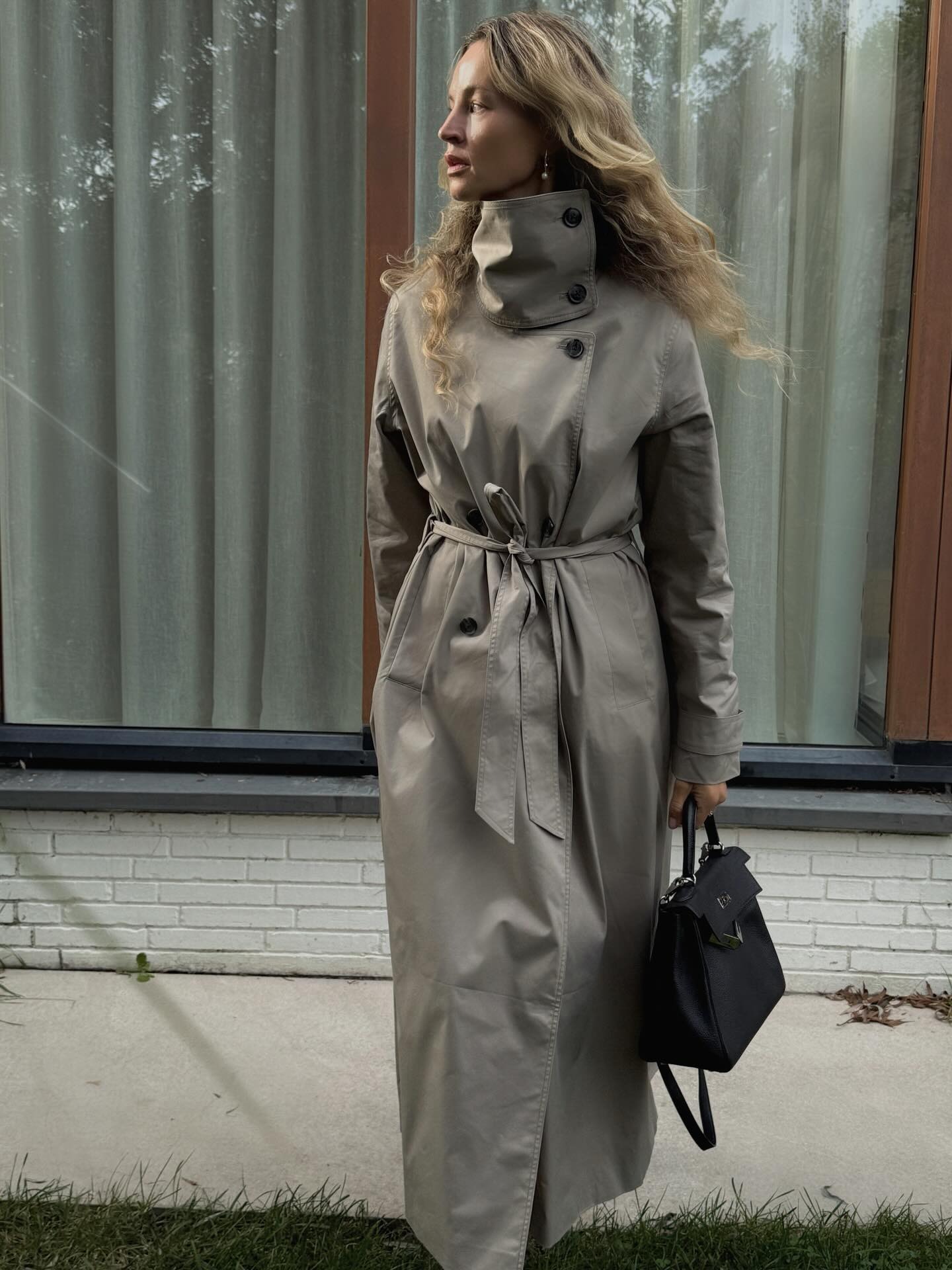 Influencer wears a high-neck belted trench coat.