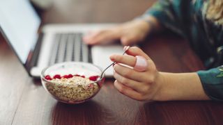 Doctor reveals why you shouldn't eat porridge - woman eating porridge whilst working