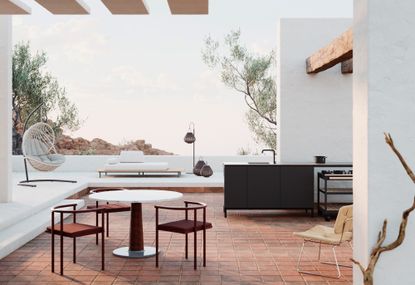 Outdoor setting with of the rocks consisting of a cream hanging lounge chair, White sofa with a wooden base, 1 hanging lantern and 2 floor lanterns, outdoor kitchen sink and cooking module with wheel, white round table with brown bottom and 3 matching brown chairs
