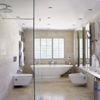 bathroom with tiles on wall and bathtub and commode