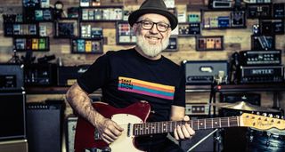 That Pedal Show's Dan Steinhardt in the studio, surrounded by amps and effects and playing his red Telecaster with a white pickguard.