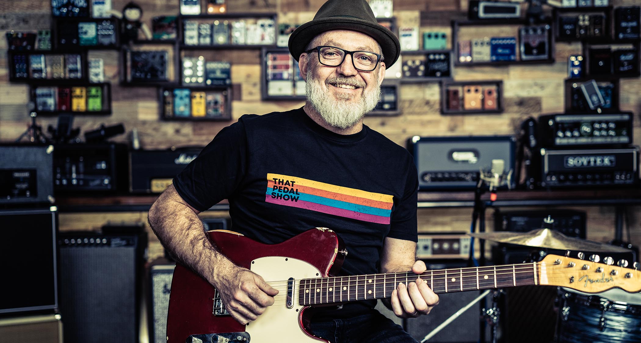 That Pedal Show&#039;s Dan Steinhardt in the studio, surrounded by amps and effects and playing his red Telecaster with a white pickguard.