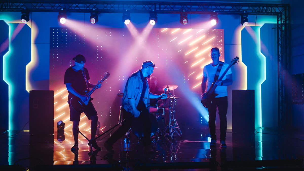 Band on stage with PA speakers and pink lights 