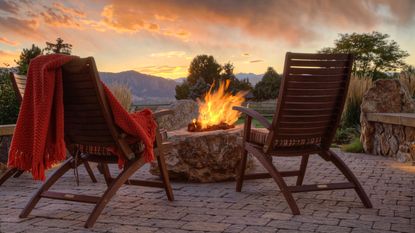 Two armchairs alongside DIY fire pit ideas on a patio at sunset