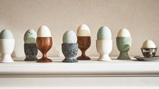 lots of different egg cups with multi colored eggs on a ledge