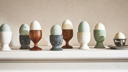 lots of different egg cups with multi colored eggs on a ledge