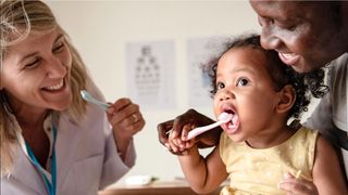 United Healthcare Golden Rule Dental Insurance review: A dentist helps a young baby brush her teeth properly