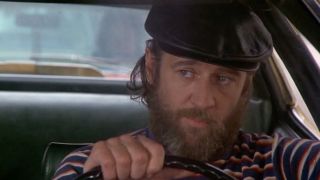 George Carlin wearing a cabbie hat and driving a taxi cab in 1976's Car Wash.