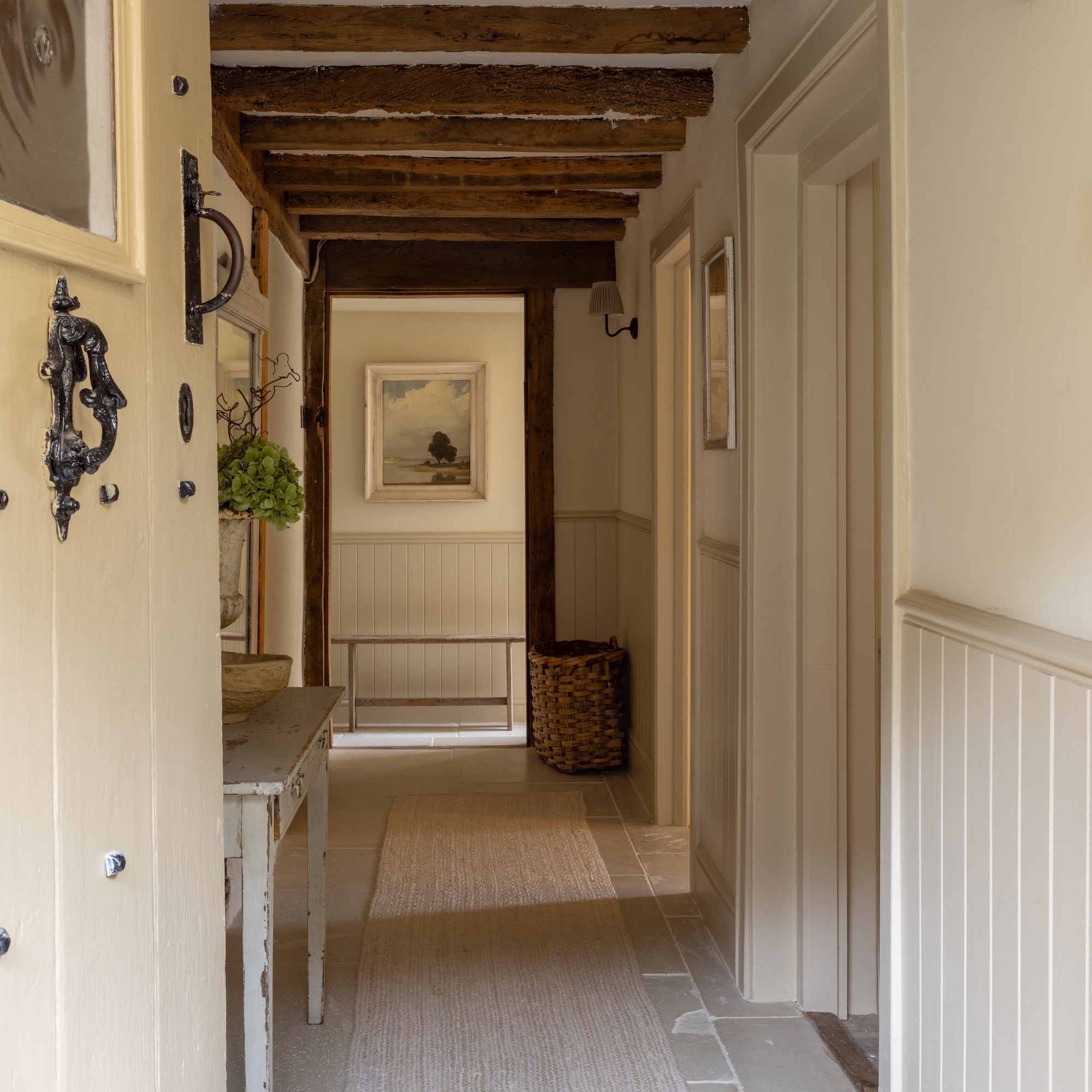 cream painted door opening onto a hallway with stone flooring and cream painted walls and tongue-and-groove panelling