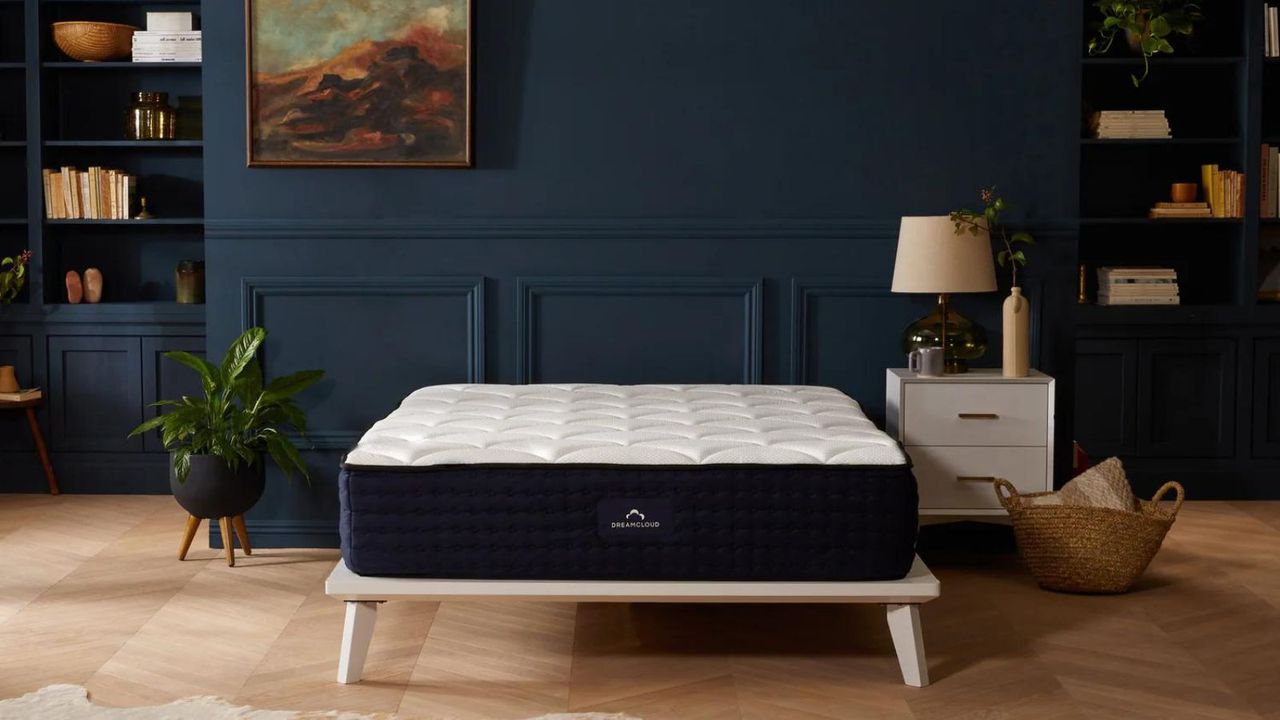 DreamCloud Luxury Hybrid Mattress on a bed against a blue wall.