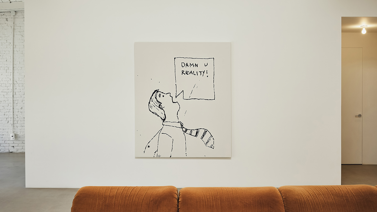 white wall with art on it and brown sofa playlab