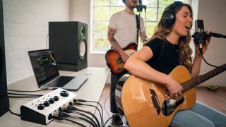 Two guitarists recording next to a desk with a laptop, speakers and Blackstar Polar 4 audio interface