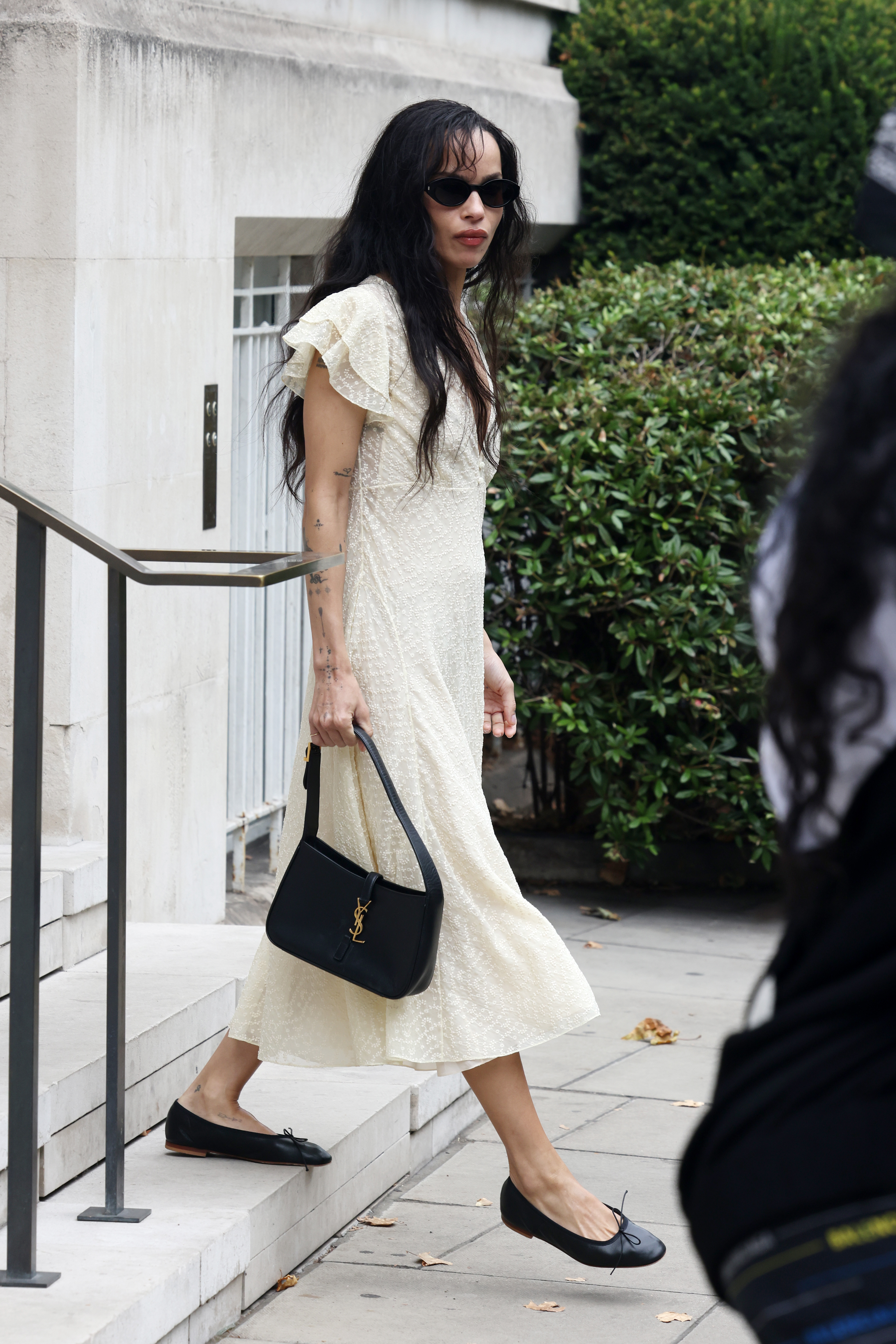 An image of Zo&amp;euml; Kravitz wearing a floral dress, ballet flats and shoulder bag as part of her autumn capsule wardrobe.