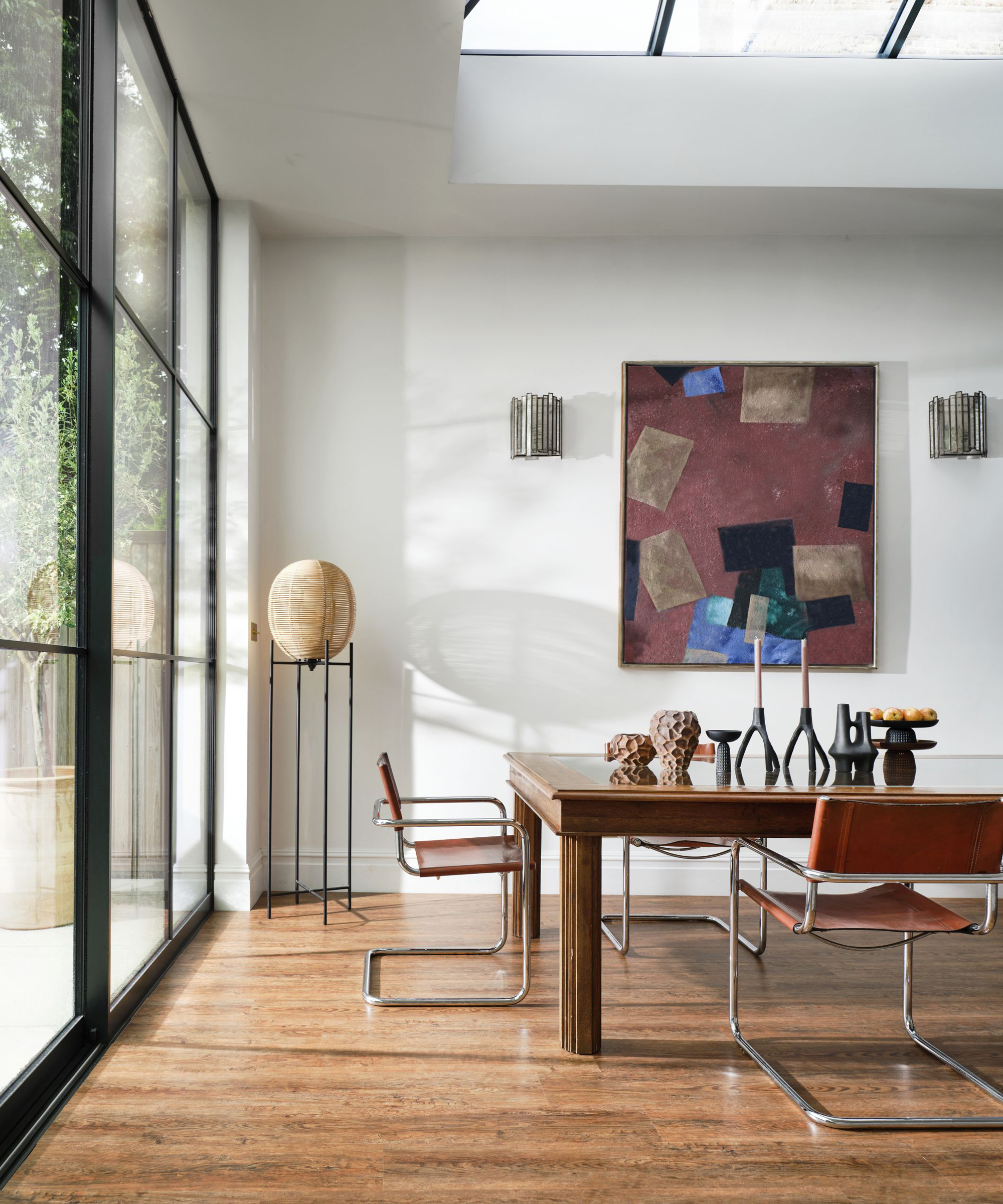 A dining room color idea with white walls, black details on french windows, and warm wooden floors and table