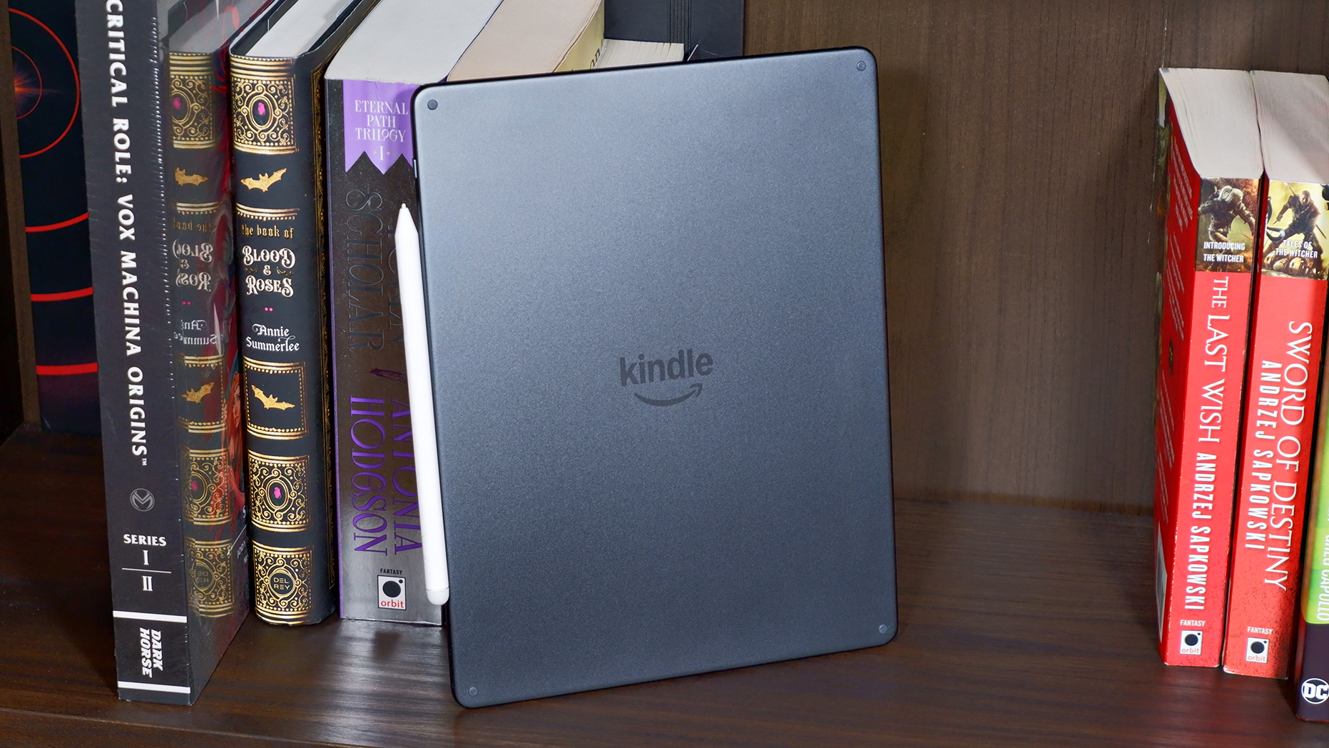 Amazon Kindle Scribe Colorsoft on a bookcase, focusing on the back of the e-reader.