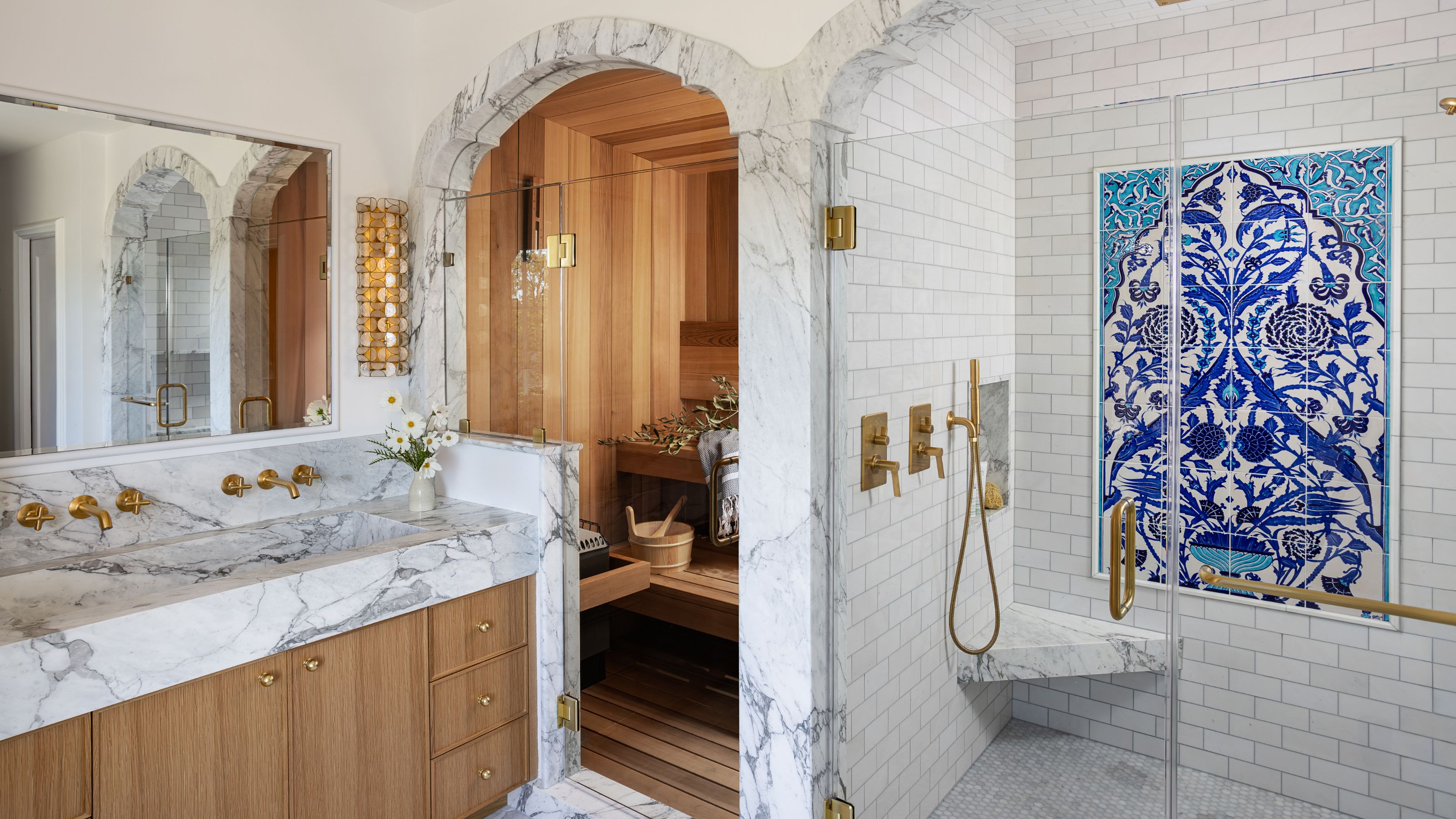 a large primary ensuite with marble trimmed arches into a sauna and shower