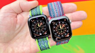 Close-up of the Apple Watch SE 3 and Apple Watch Series 11 in a user's hand with a colorful, out-of-focus background
