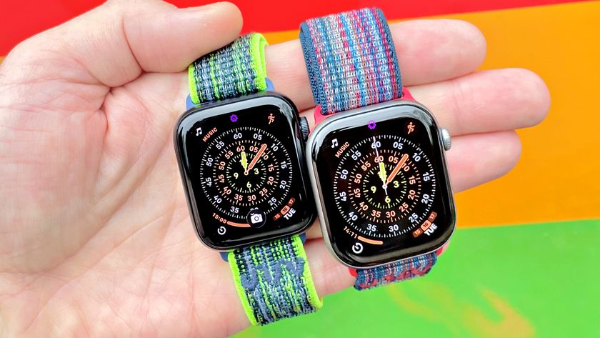 Close-up of the Apple Watch SE 3 and Apple Watch Series 11 in a user's hand with a colorful, out-of-focus background
