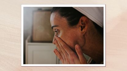 A woman pictured with her hair pulled back by a hairband, pressing skincare into her cheeks with her fingers/ in a cream, textured template