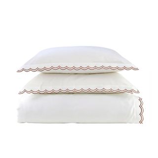 A white duver cover and pillow case set with red scalloped edges