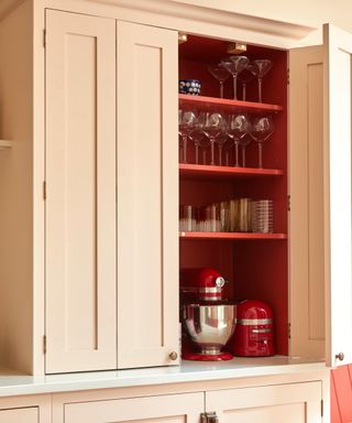 tall pale pink kitchen cabinet with door open and inside painted red