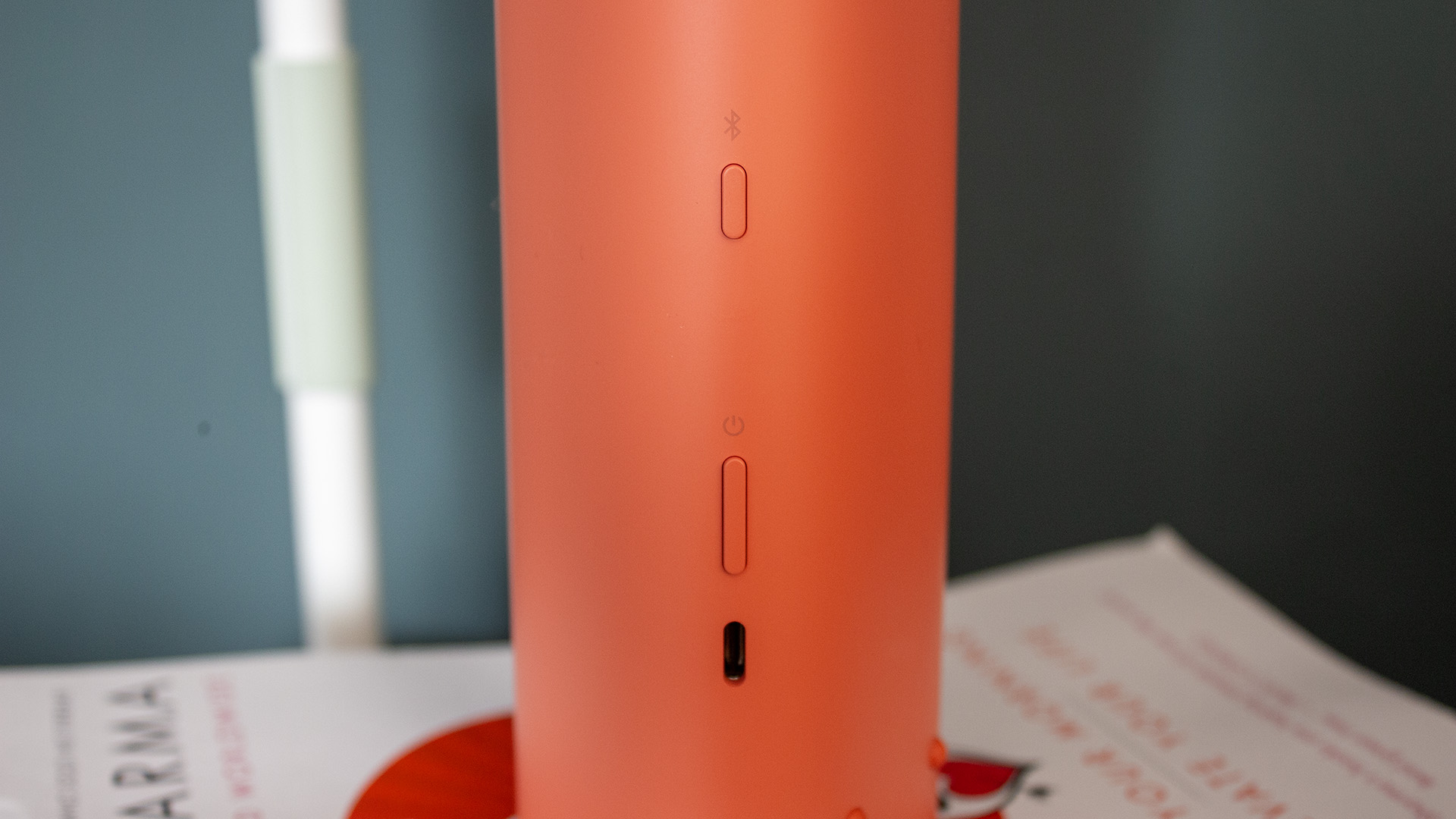 a red sonos roam 2 speaker in a living room on top of a red book