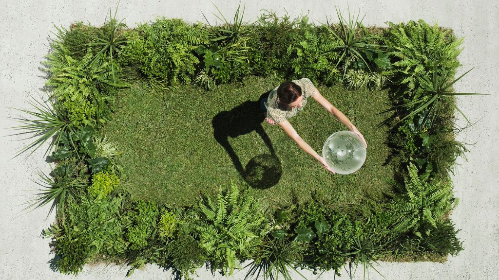 A woman dances on grass holding a glass globe