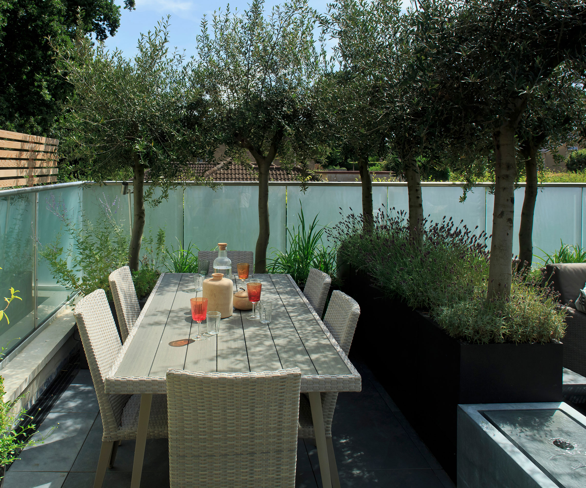 private outdoor dining area with water feature and olive trees