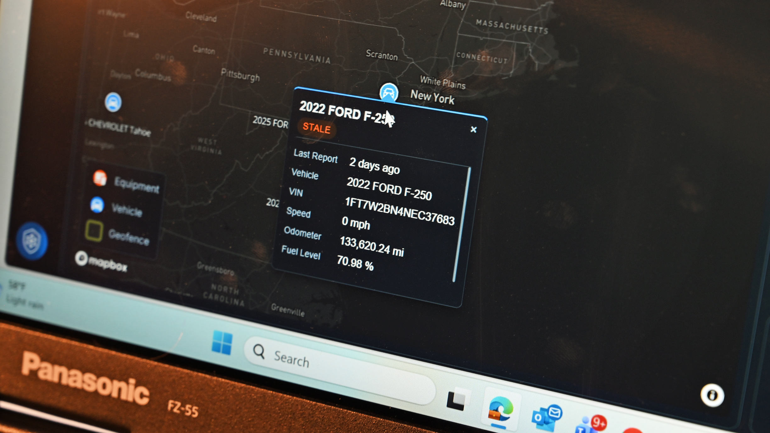 Close-up of a Panasonic FZ-55 display running fleet intelligence software, showing map tracking data for a Ford F-250.