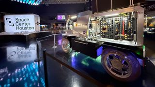 a golf cart-size mockup of a lunar rover is seen on display at a space museum