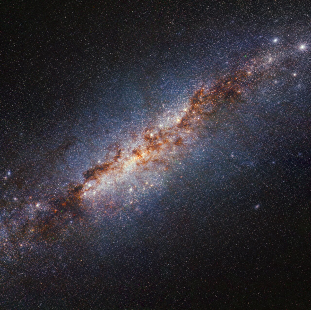 A section of M82 as imaged by Webb. An edge-on spiral starburst galaxy with a bright white, glowing core set against the black background of space. Dark brown tendrils of dust are scattered heavily toward the galaxy’s centre. Many white points in various sizes — stars or star clusters — are scattered throughout the image, but are most heavily concentrated toward the center.