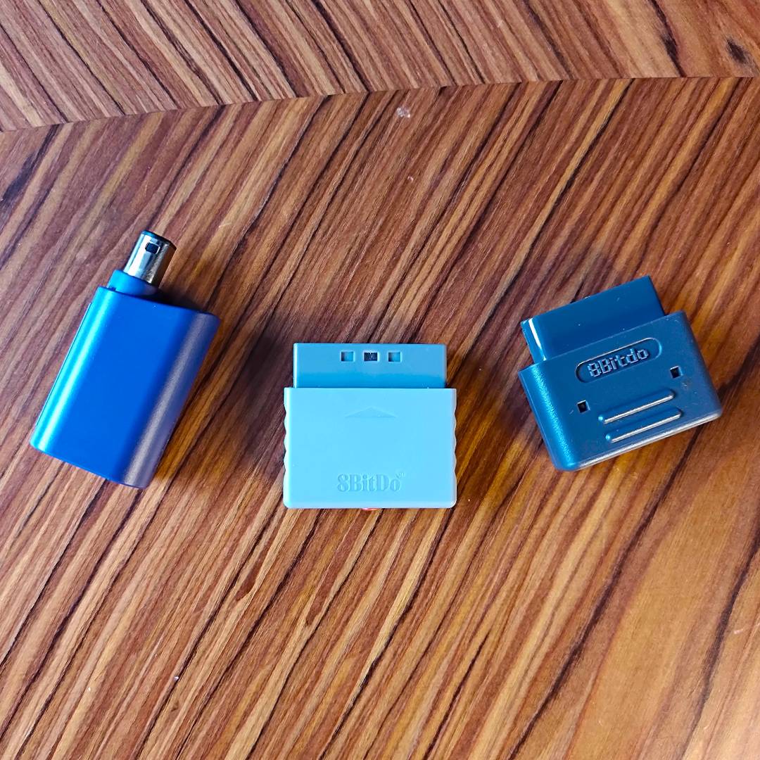 8Bitdo GameCube, PS1, and SNES Retro Receivers on a woodgrain table.