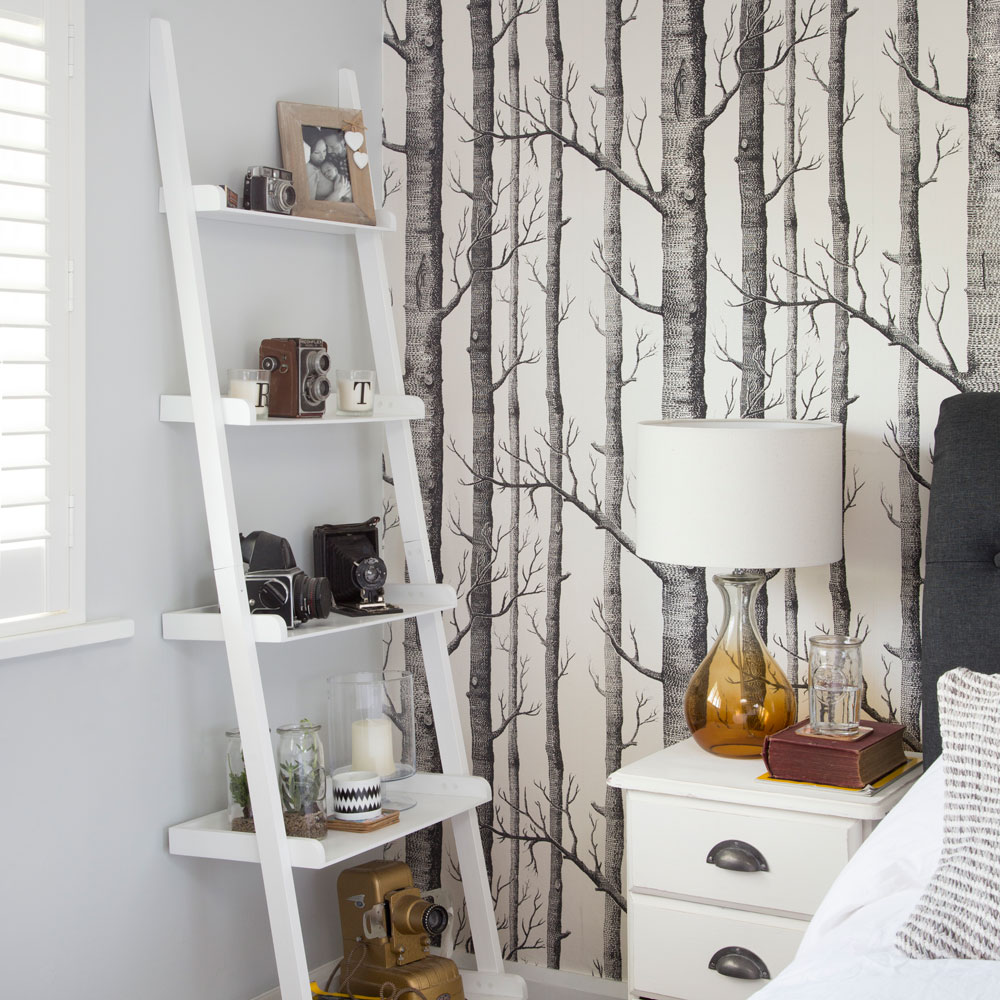 Bedroom with woodland wallpaper, ladder shelves and white side table