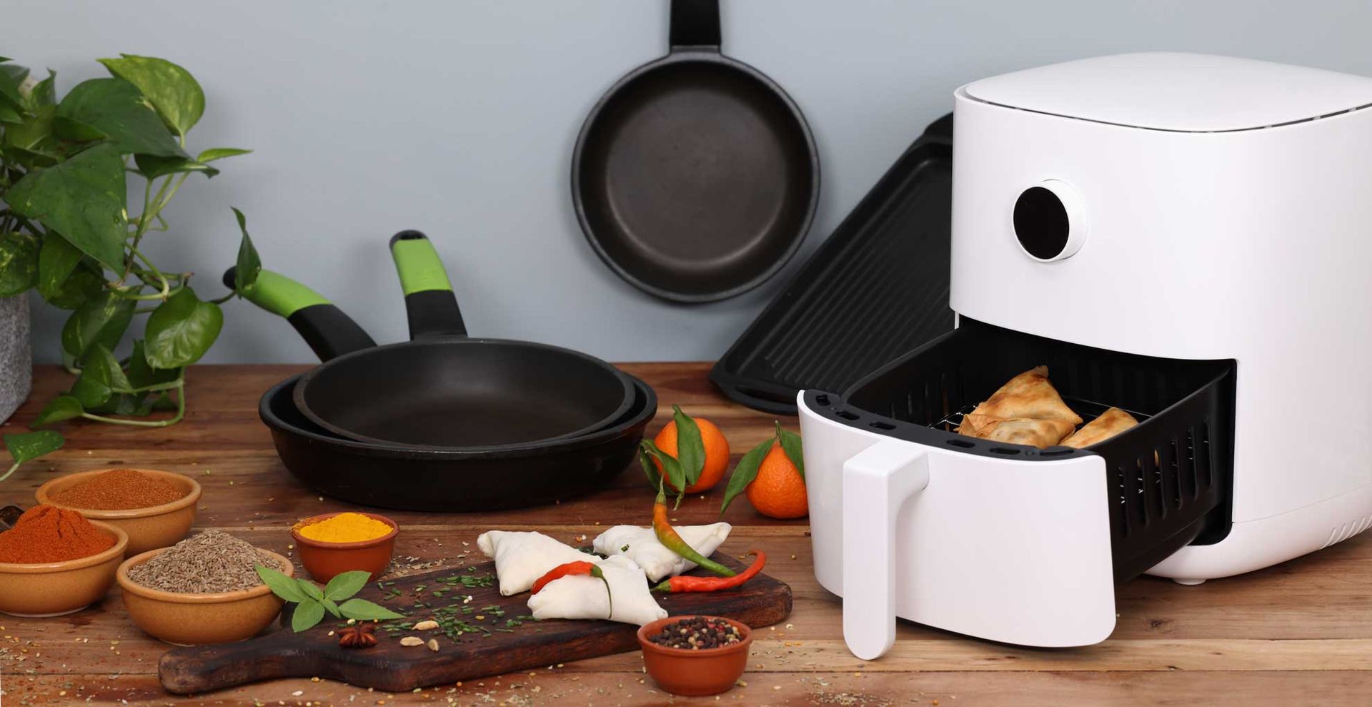 Air fryer in a kitchen with a chopping board filled with healthy ingredients