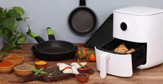 Air fryer in a kitchen with a chopping board filled with healthy ingredients