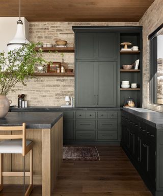 kitchen with dark gray cabinets, wood floors, brick wall and island unit