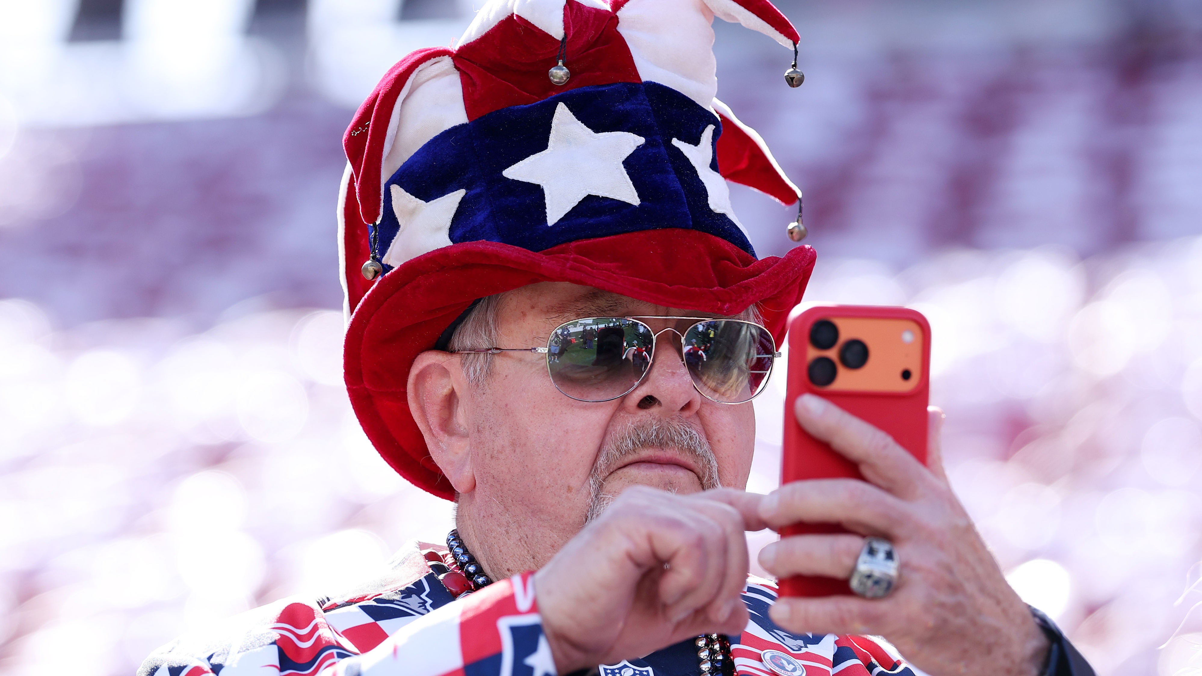 Super Bowl fan in stars and stripes hat and jacket looking on his phone how to watch Peacock free ahead of the Patriots Seahawks NFL game on Feb 8 2026