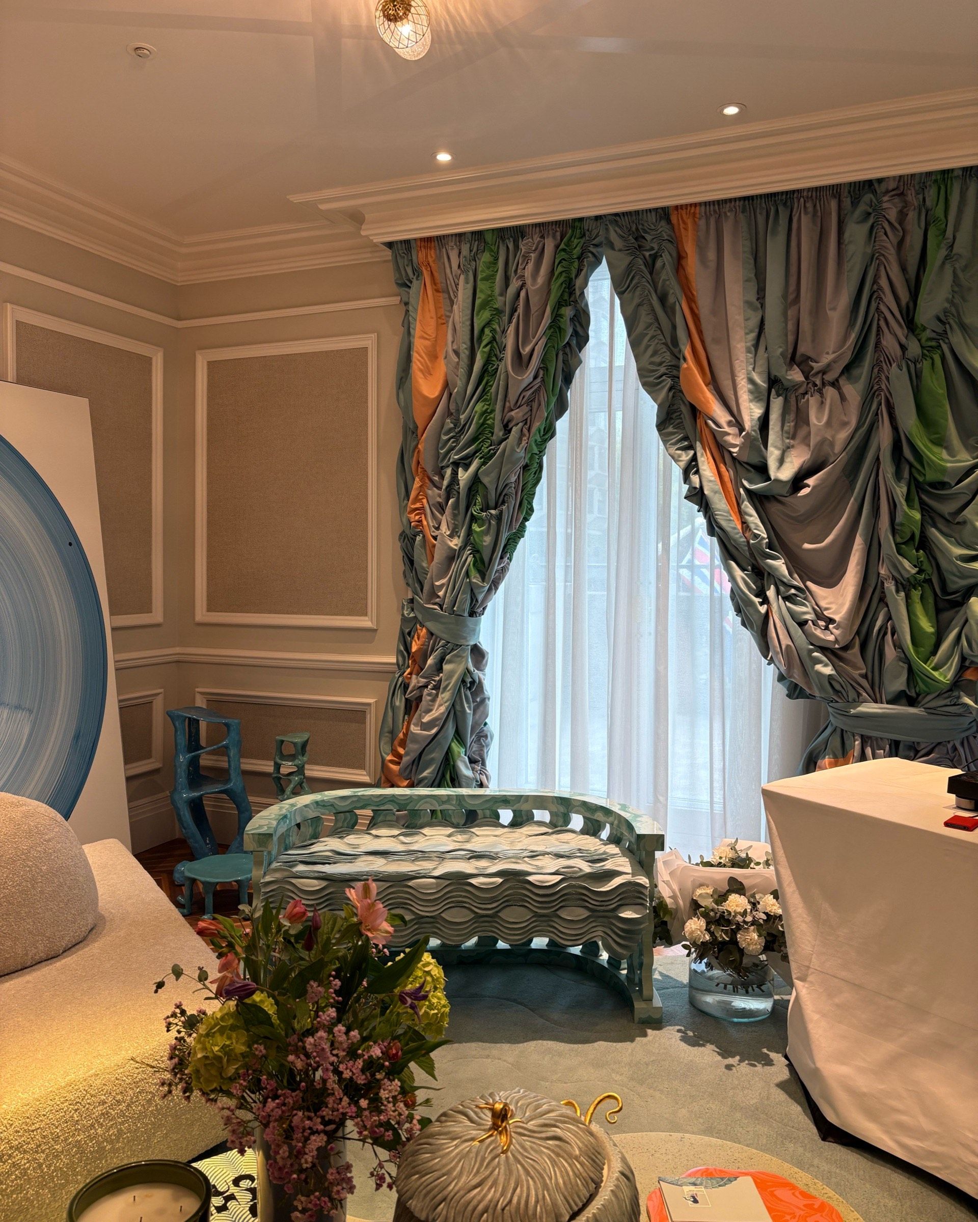 A lavish hotel suite filled with whimsical, sea green and blue-tinted homeware, curtains, and accessories.