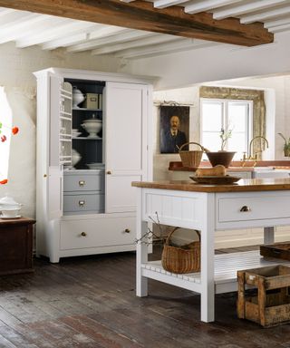 white freestanding larder unit and island in kitchen with natural wooden floor