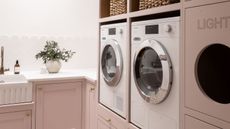 A laundry room with pink built-in cabinetry with a lifted washing machine and dryer