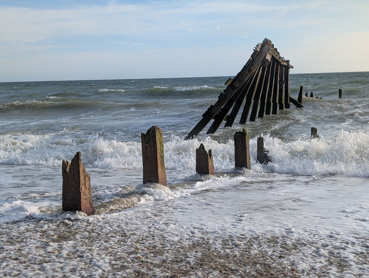 A damaged groyne on a UK beach, the high tide is smashing into it