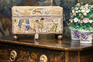 An antique box and ceramic flower decorations on an inlaid wooden chest