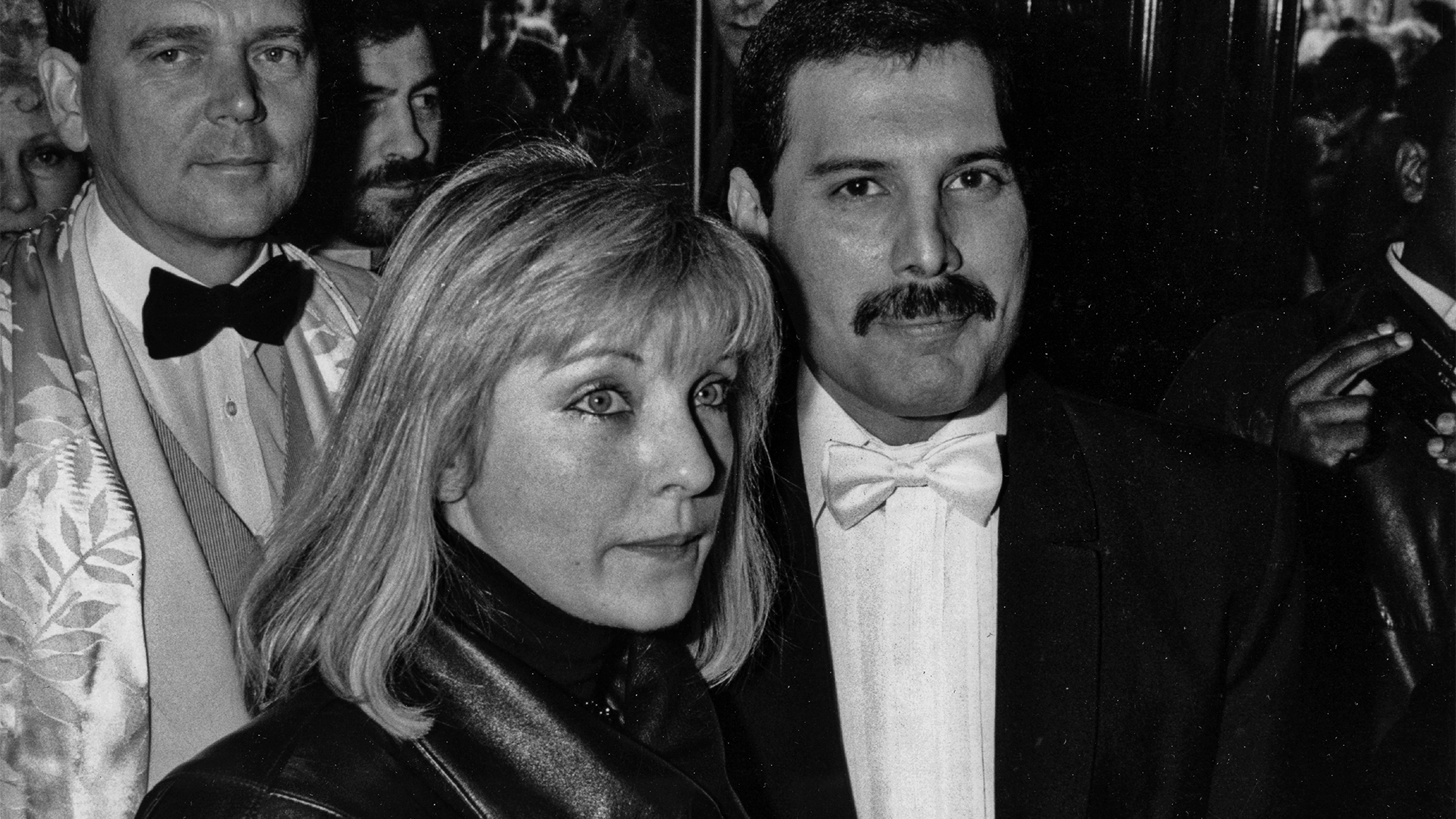 Freddie Mercury with his friend Mary Austin at an after-party in London for 'Dave Clark's Time - The Musical', 9th April 1986. Behind them is Queen's manager Jim Beach