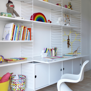 White modular shelving system, open shelves contain books and cuddly toys, closed cabinets at the bottom