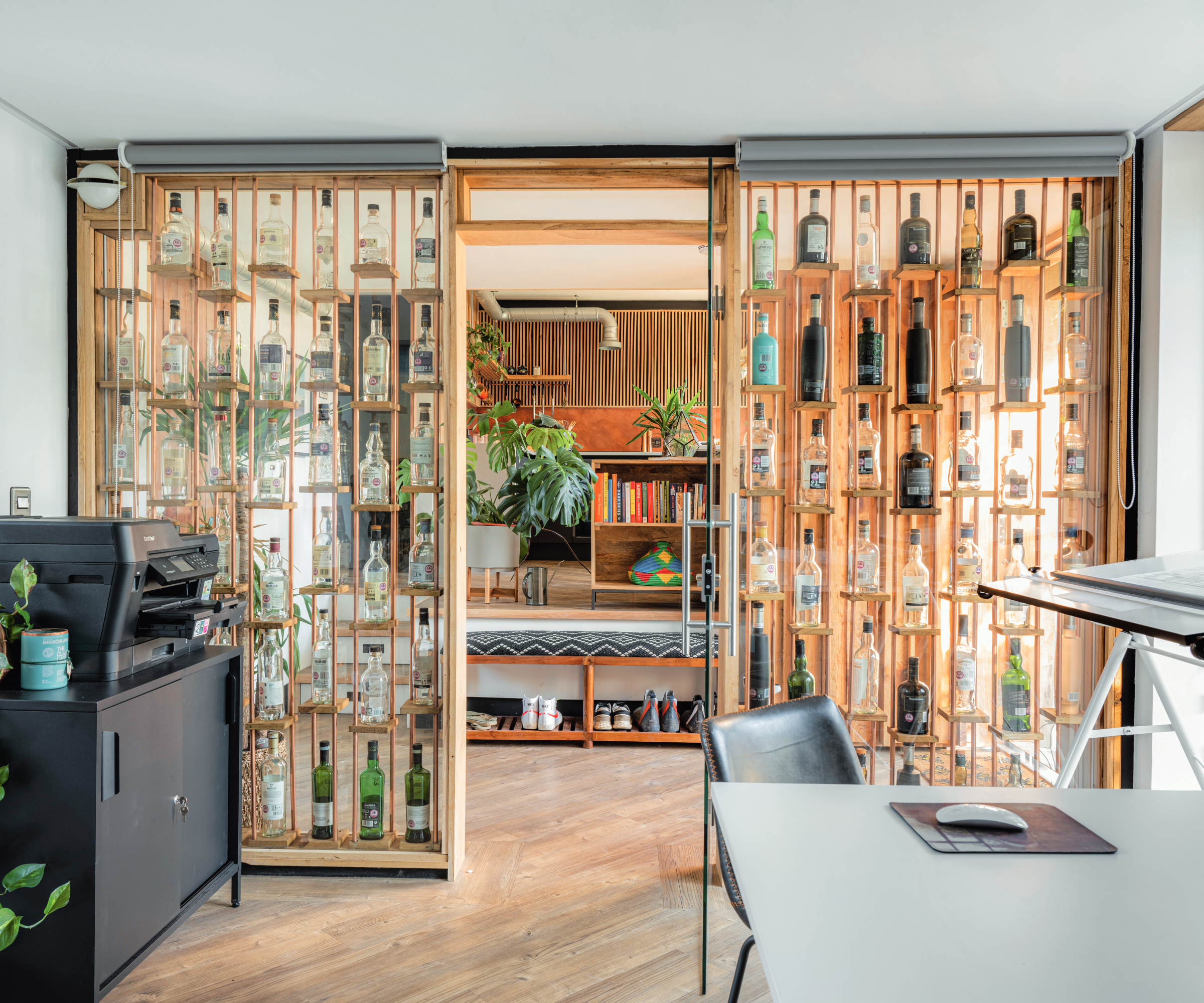 large internal walls dividing office from rest of house with shelves showcasing bottles behind windows