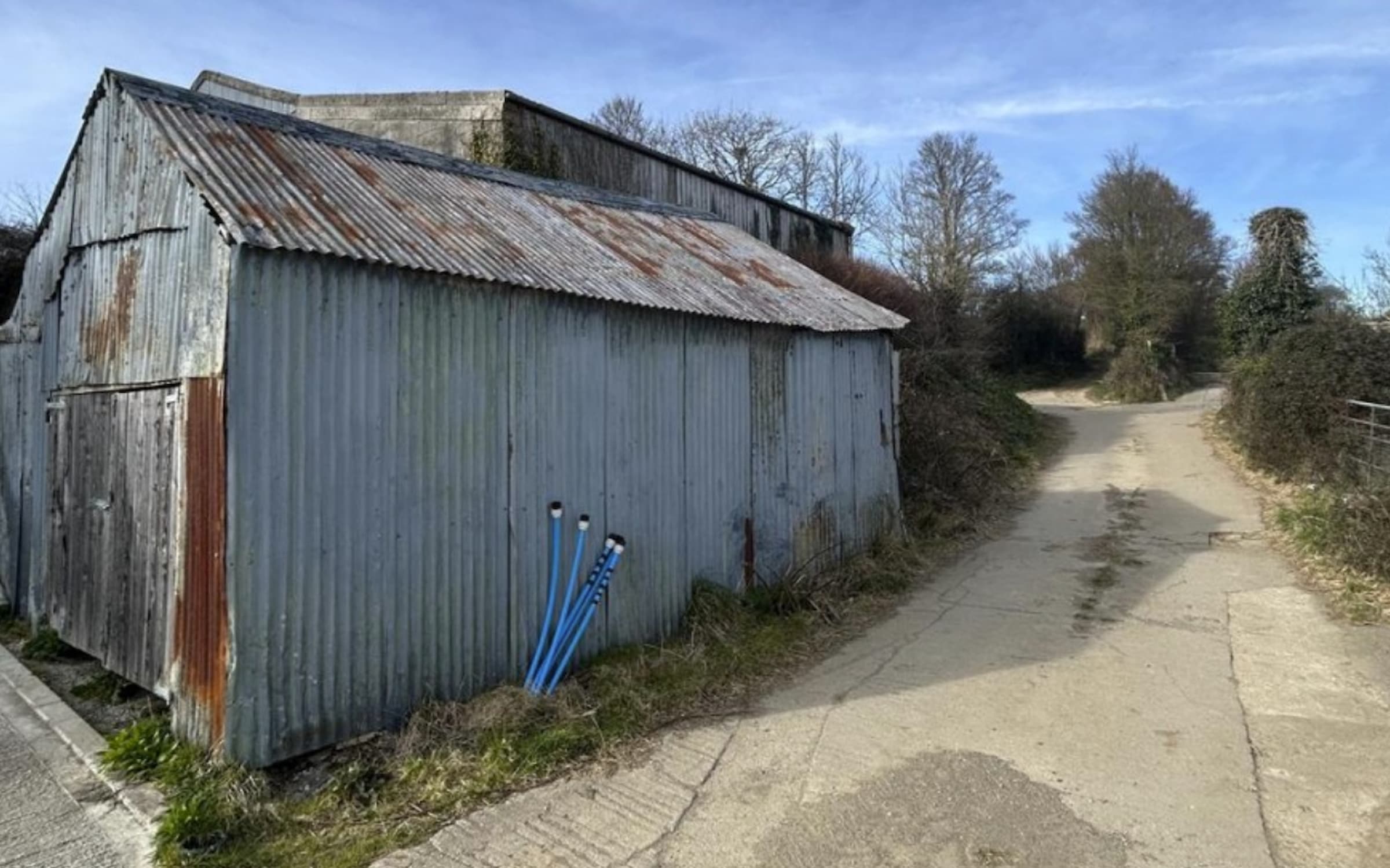 A metal garage with exposed pipes and a long driveway