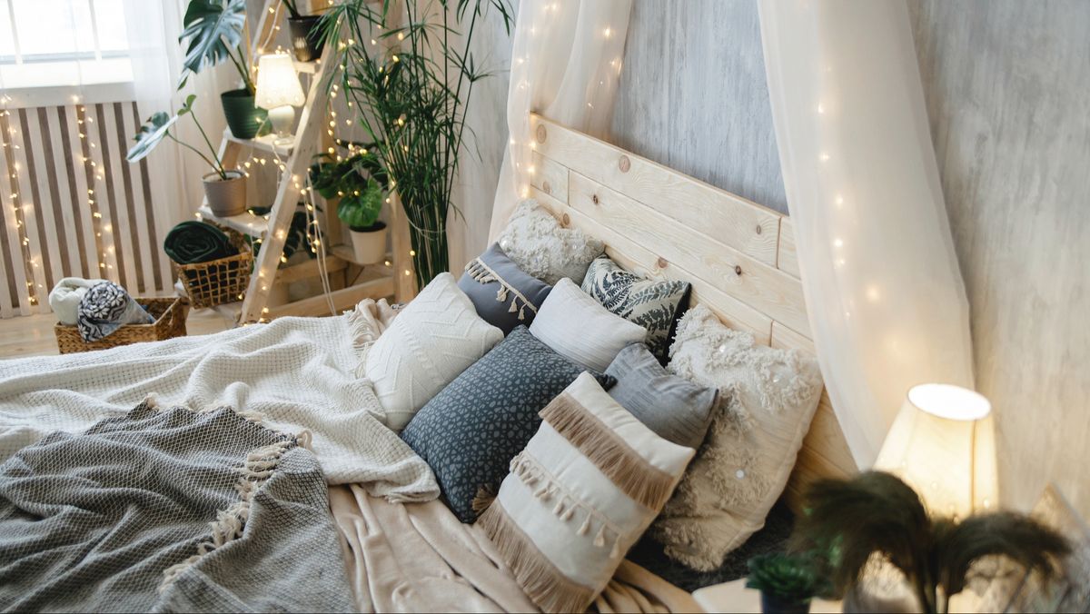 Bed with lots of blankets and pillows on it in a cosy and well decorated bedroom