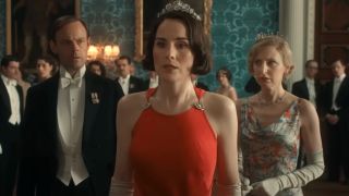 Harry Hadden-Paton and Laura Carmichael watch on in shock as Michelle Dockery stands with upset in Downton Abbey: The Grand Finale.