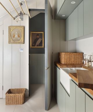 A utility room idea for a narrow space with wall and ceiling storage solutions and wood panelling.