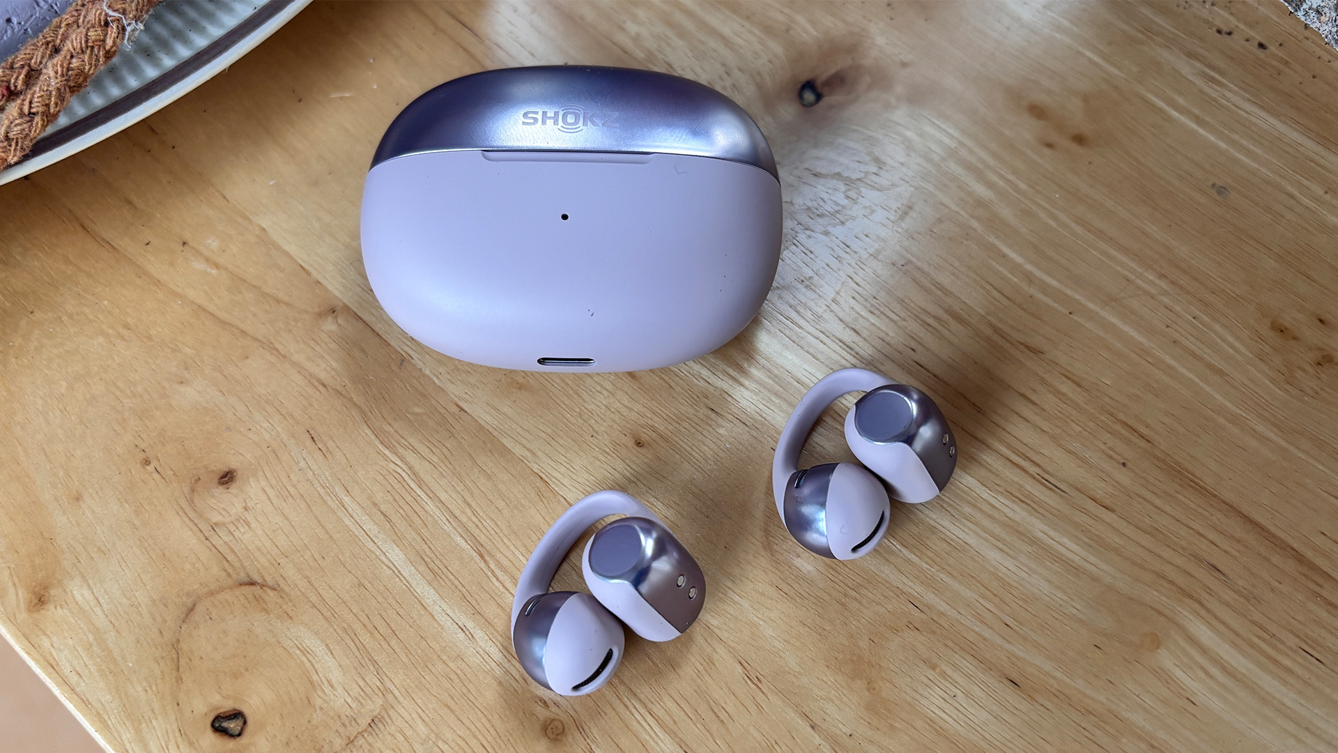 Shokz OpenDots One open earbuds on wooden table next to case